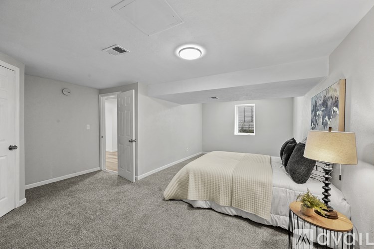 A bedroom with a bed, lamp, and a painting on the wall.