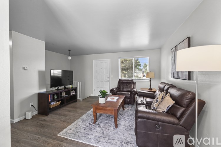 A living room with a brown leather couch, a wooden coffee table, and a flat-screen TV.