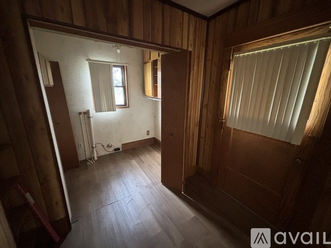 A room with wooden walls and a window with blinds.