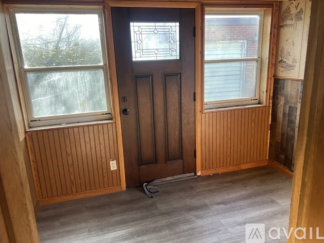 A room with a wooden door and two windows.