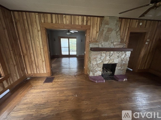 A room with wooden walls and a stone fireplace.