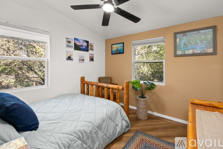 A bedroom with a bed, a ceiling fan, and pictures on the wall.