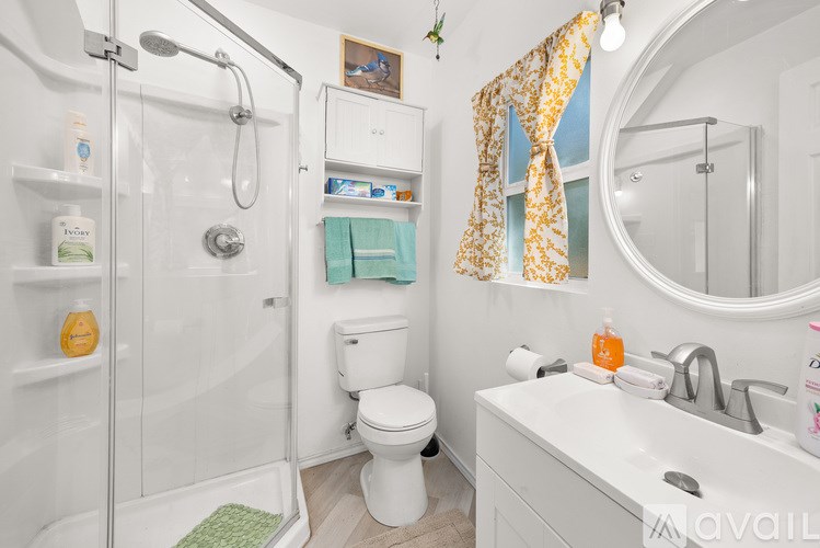 A bathroom with a white toilet, sink, and shower.