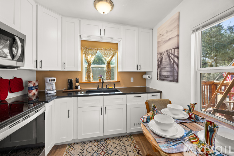 A kitchen with white cabinets and a black countertop.