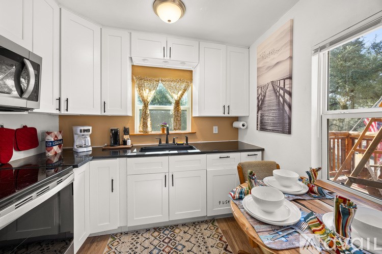 A kitchen with white cabinets and a black countertop.