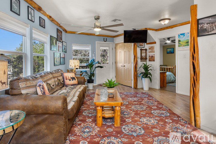 A living room with a brown leather couch, a glass coffee table, and a rug with a floral pattern.