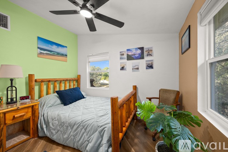 A bedroom with a bed, a chair, a ceiling fan, and pictures on the wall.