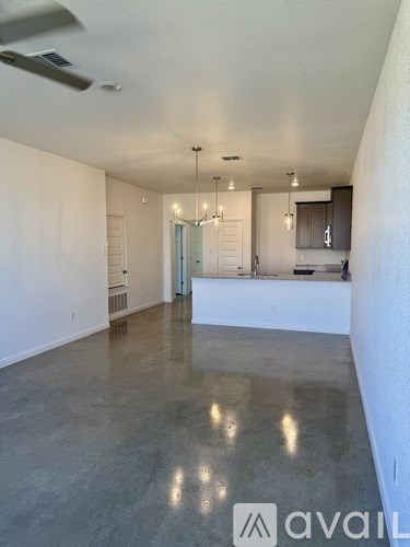 A spacious room with a kitchen area in the background.