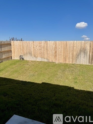 A wooden fence with a small green lawn in front of it.