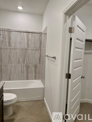 A bathroom with a toilet, tub, and a white door.