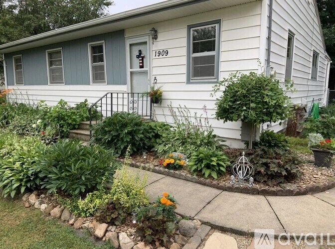 A house with a grey front and a white door with a number 1909 on it.