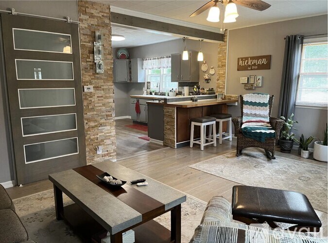 A modern kitchen with a stone pillar and a dining table with a bench.