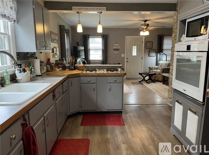 A kitchen with wooden floors and a red rug in the middle.