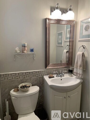 A bathroom with a toilet, sink, and mirror.
