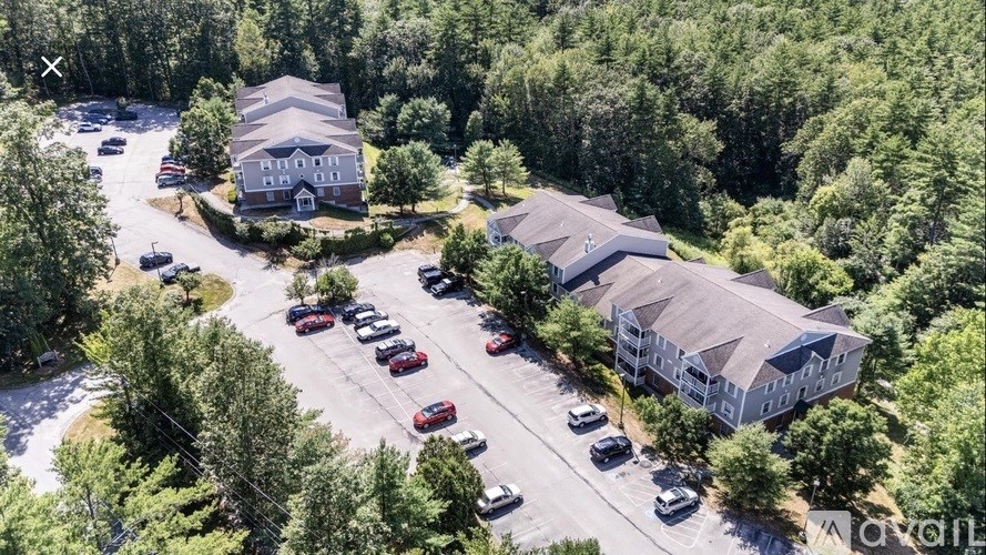 A bird's eye view of a parking lot with cars and two buildings.