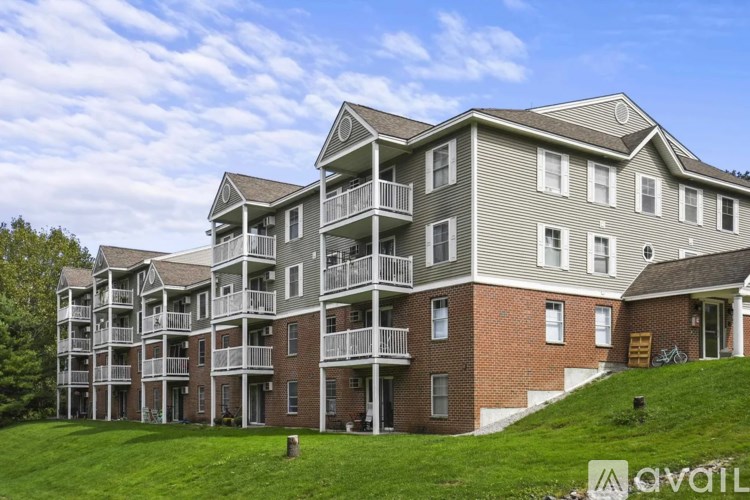 A large apartment building with multiple balconies and a grassy area in front.