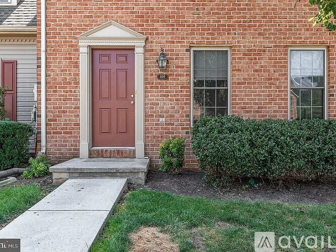 A red door is on the left side of a brick house.