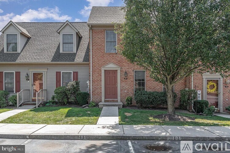 A red brick house with a tree in front.
