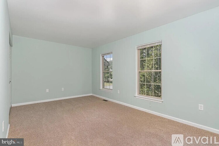 A room with a carpeted floor and two windows.