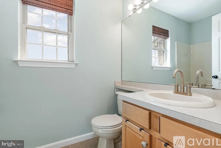 A bathroom with a toilet, sink, and mirror.