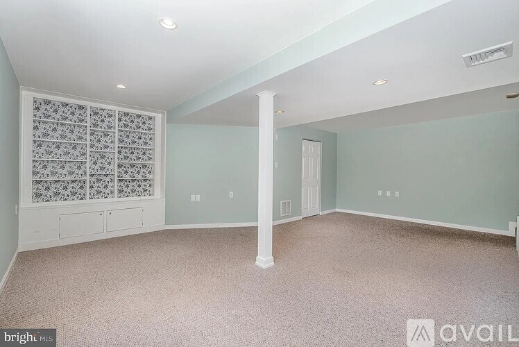 A spacious room with a carpeted floor and a window with a decorative screen.