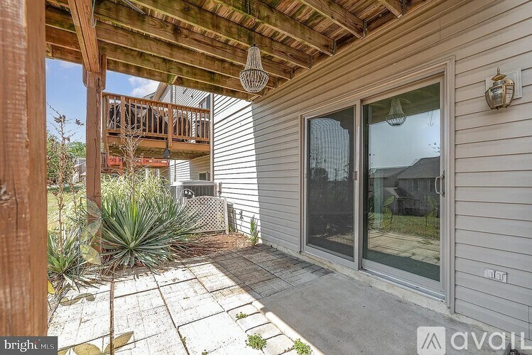 A patio area with a wooden pergola and sliding glass doors.