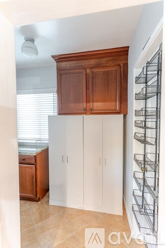 A kitchen with white cabinets and a wooden cabinet above a counter.