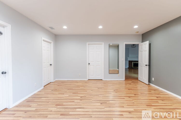 A room with wooden floors and white walls, with a door on the left and a glass door on the right.