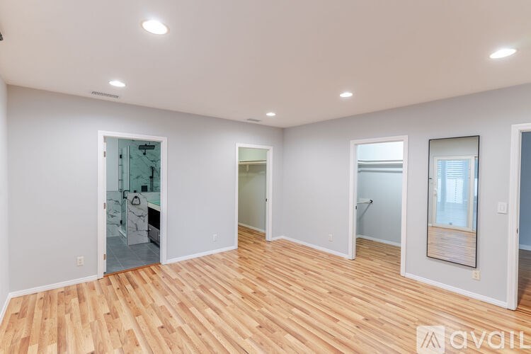 A spacious room with wooden flooring and white walls.