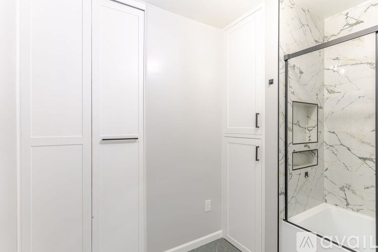 A white bathroom with a marble shower.