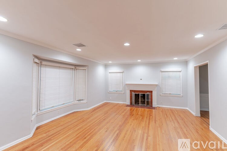 A room with wooden floors and a fireplace in the middle.