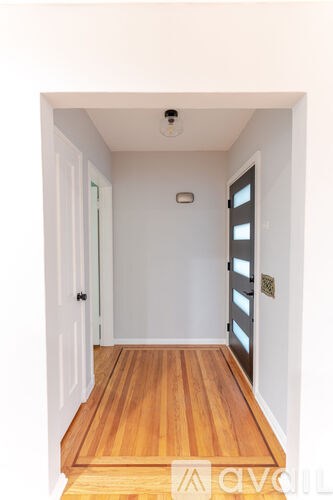 A hallway with a wooden floor and white walls.