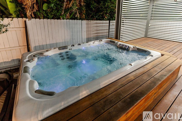 A hot tub on a wooden deck with a white fence in the background.