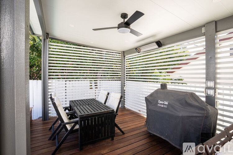 A patio with a table, chairs, and a grill.