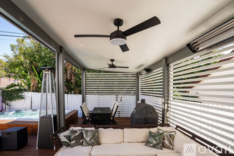 A patio with a white couch, a ceiling fan, and a hot tub.