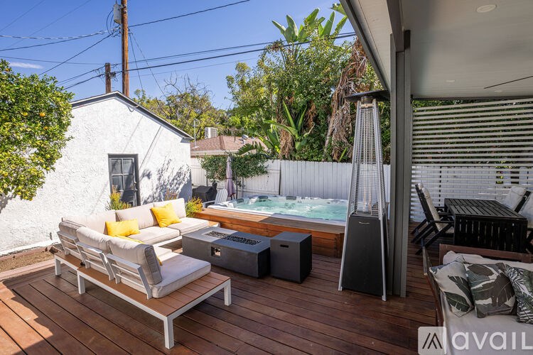 A patio with a white couch, a table, and a hot tub.