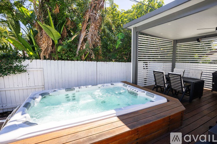 A hot tub is surrounded by a wooden deck and patio furniture.