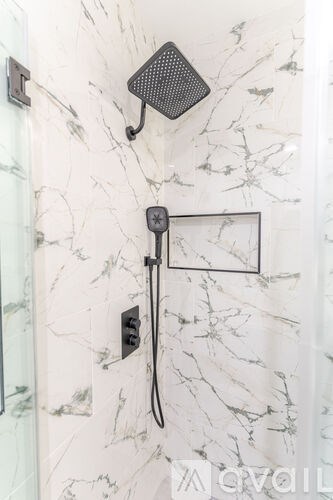 A shower with a black handle and a black square plate.