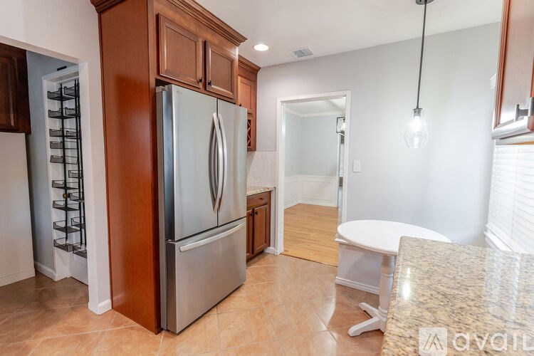 A kitchen with a stainless steel refrigerator and wooden cabinets.