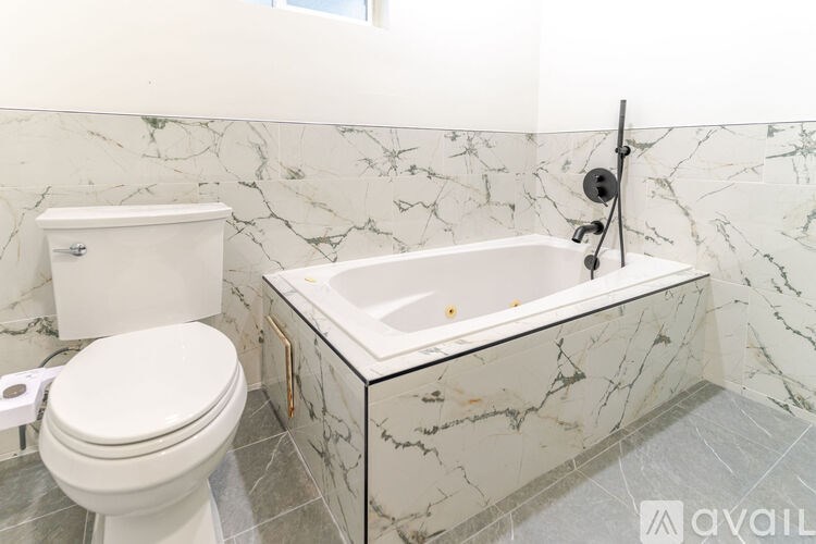 A white toilet sits next to a marble sink in a bathroom.