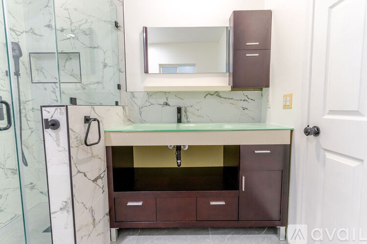 A bathroom with a marble wall and a glass shower door.
