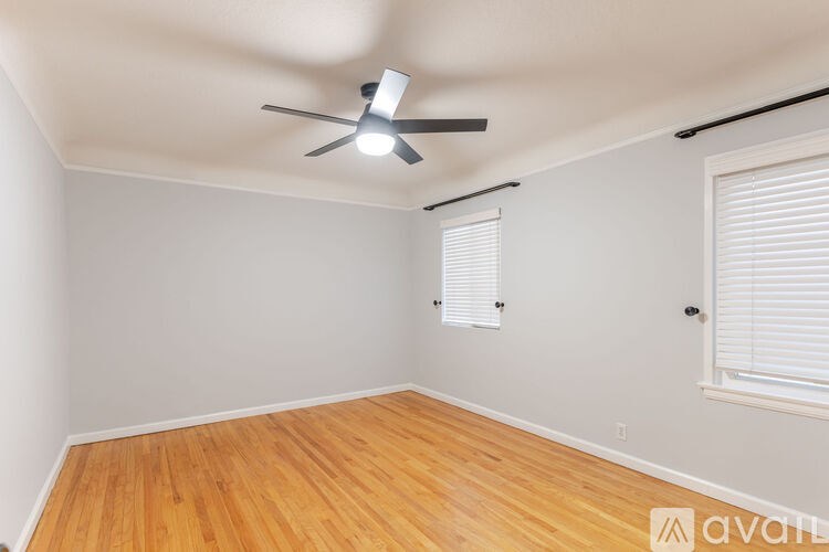 A room with a ceiling fan and wooden flooring.