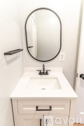 A white sink in a bathroom with a round mirror above it.