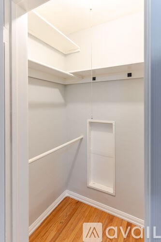 A small, empty room with a wooden floor and white walls.