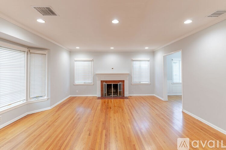 A spacious room with wooden floors and a fireplace.