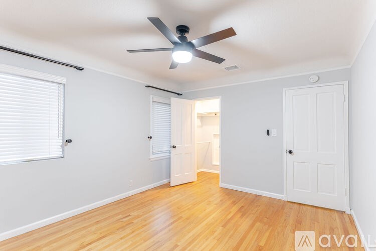 A room with a ceiling fan and wooden flooring.