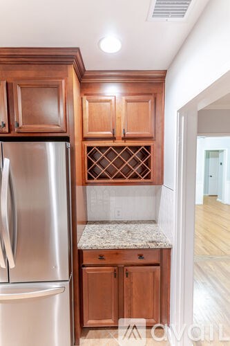 A kitchen with wooden cabinets and a stainless steel refrigerator.