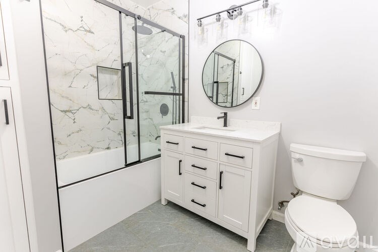 A white bathroom with a marble shower and a toilet.