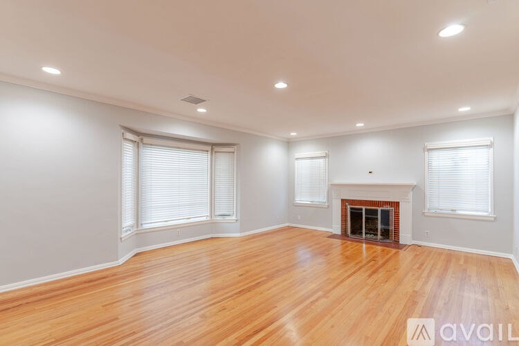 A spacious room with wooden floors and a fireplace.
