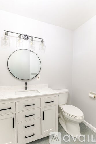 A white bathroom with a toilet, sink, and mirror.